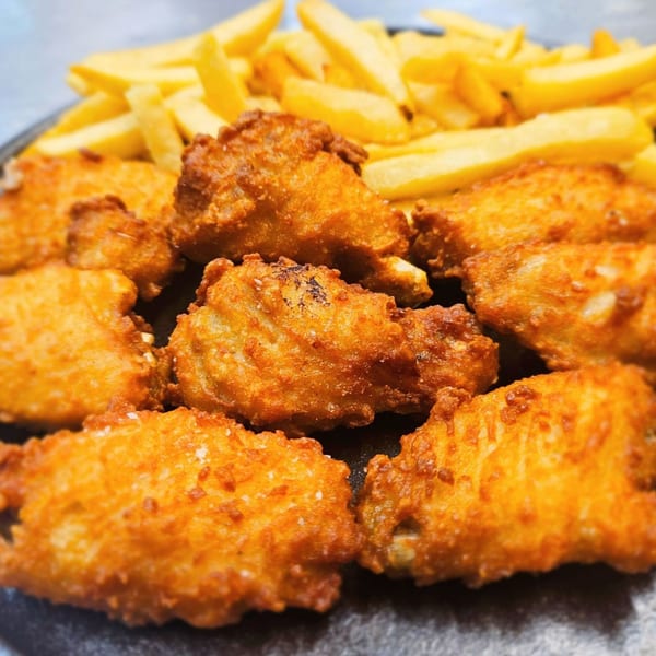 Crispy fried chicken wings and golden french fries on a dark plate.